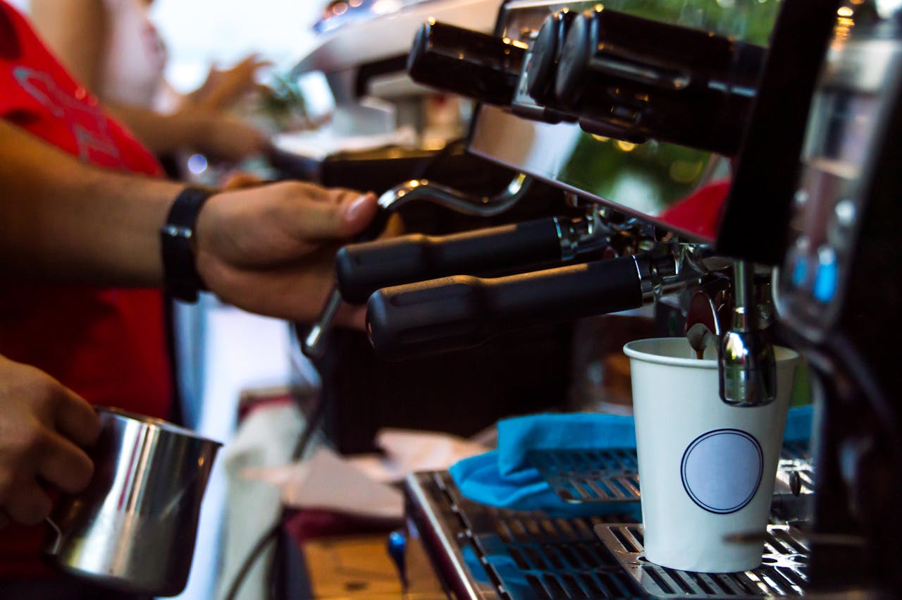 A barista making espresso in a modern café using a professional coffee machine.