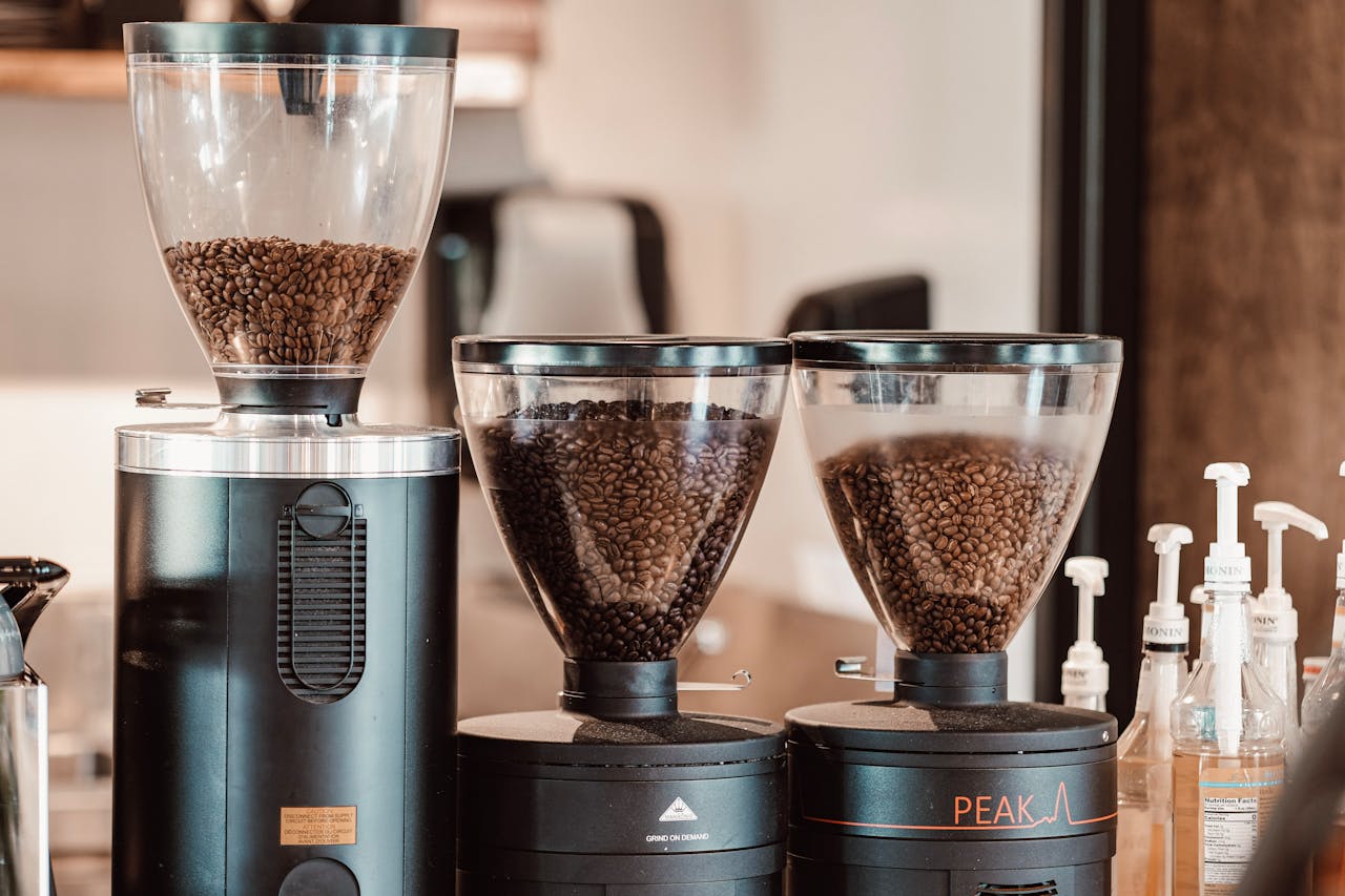 Close-up of coffee grinders filled with roasted beans in a modern cafe setting.
