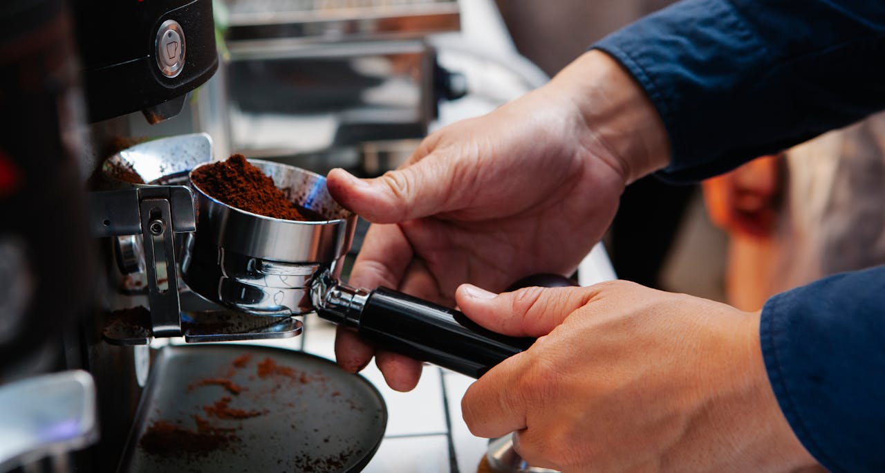 A barista is using an espresso machine to prepare coffee with freshly ground beans.